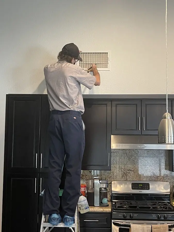 Technician inspecting an air vent during HVAC service in Frankstown